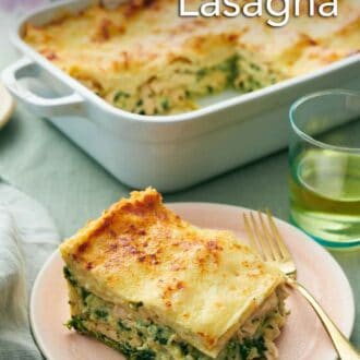 Pinterest graphic of a plate with a slice of chicken lasagna with a fork. The rest of the lasagna in the background with a drink and some flowers.