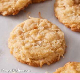 Pinterest graphic of coconut cookies on a marble surface with shredded coconut scattered around.