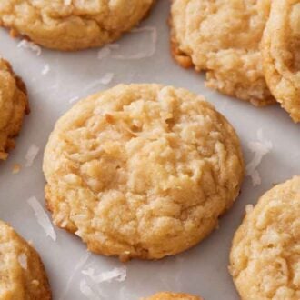 Coconut cookies on a marble surface with shredded coconut scattered around.