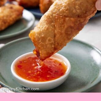 Pinterest graphic of an egg roll dipped into a bowl of sauce.