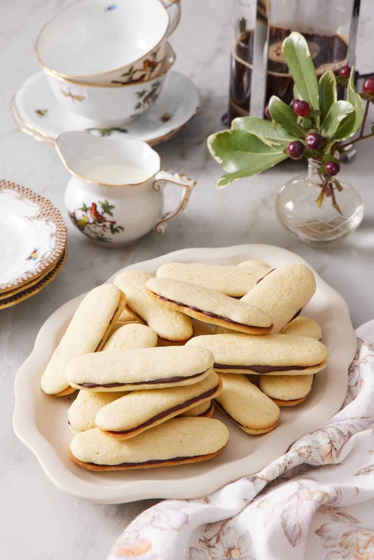 A platter of Milano cookies. Coffee, cream, and cups in the background along with some decorative plants.