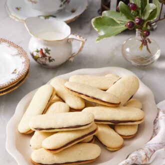 Pinterest graphic of a platter of Milano cookies. Coffee, cream, and cups in the background.