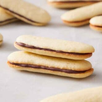 Two Milano cookies, stacked, with more cookies in the background.