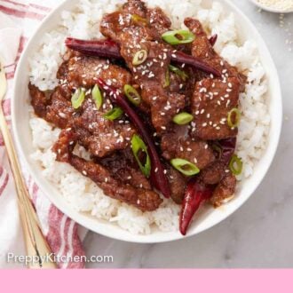 Pinterest graphic of an overhead view of Mongolian beef over rice topped with green onions and sesame seeds.