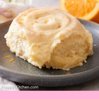 Pinterest graphic of an orange roll on a plate with cut oranges in the background.