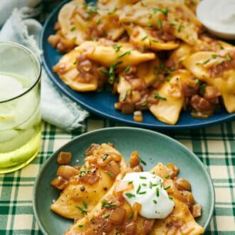 Pinterest graphic of a plate with pierogies topped with sour cream and chives with a platter with more in the background.