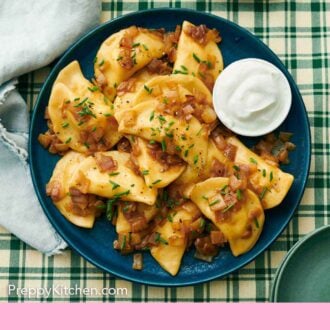 Pinterest graphic of a platter with multiple pierogies topped with chives and sour cream.