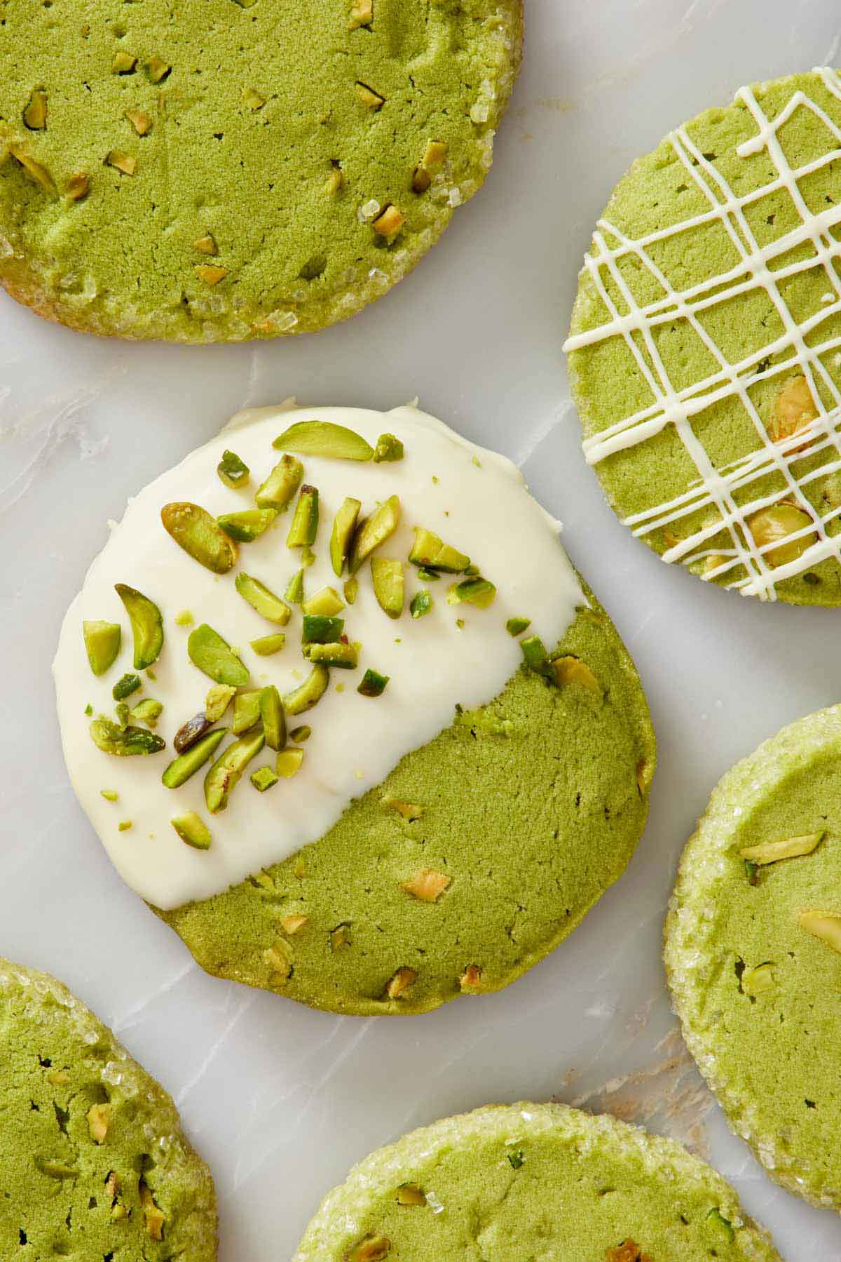 Overhead view of pistachio matcha cookies with various icing styles.