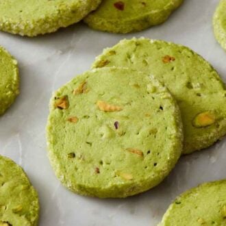 Pistachio matcha cookies on a marble surface with one overlapping another.