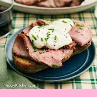 Pinterest graphic of a plate with a thick piece of bread topped with sliced roast beef and horseradish sauce with chives.