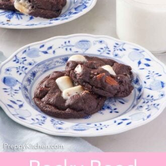 Pinterest graphic of a plate with two rocky road cookies with a glass of milk in the back along with another plate of cookies.