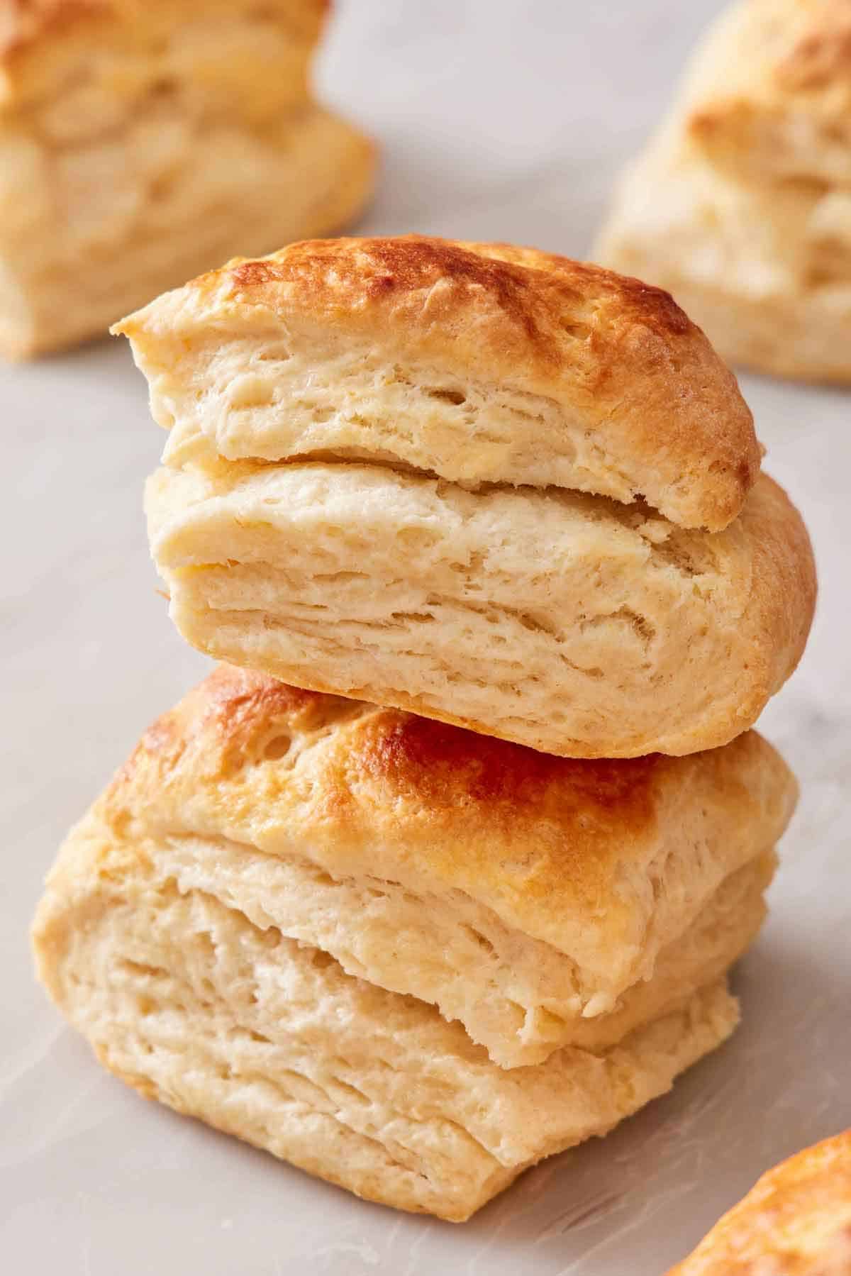 Two sourdough biscuits stacked on top of each other with more in the background.