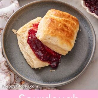 Pinterest graphic of a plate with a sourdough biscuit cut in half with jam in between.