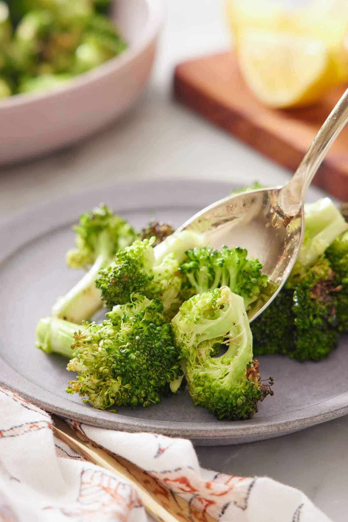 A spoonful of air fryer broccoli spooned on a plate.