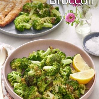 Pinterest graphic of a pink plate of air fryer broccoli with lemon wedges. A vase of flowers in the back along with a plate of fried cutlet, broccoli, and lemon wedges.