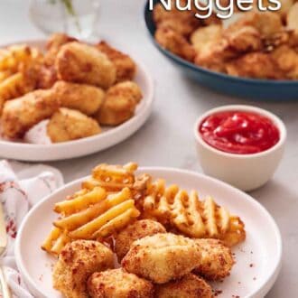 Pinterest graphic of a plate with air fryer chicken nuggets and waffle fries. A bowl of ketchup in the back along with more chicken nuggets and waffle fries.