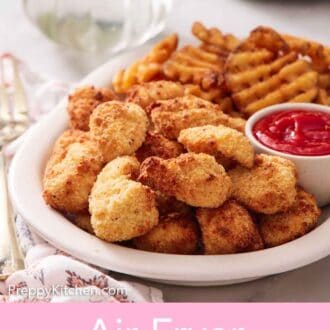 Pinterest graphic of a platter with air fryer chicken nuggets, ketchup, and waffle fries.