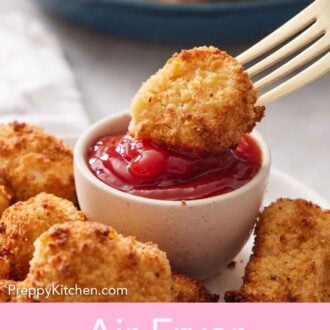 Pinterest graphic of an air fryer chicken nugget on a fork dipped into a small bowl of ketchup.