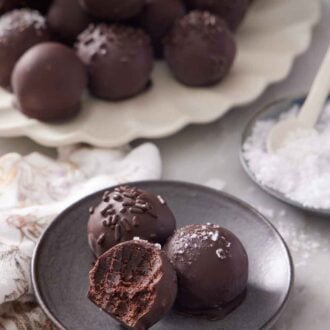 Pinterest graphic of a plate with two and a half brownie truffles. A platter of more brownie truffles in the background along.