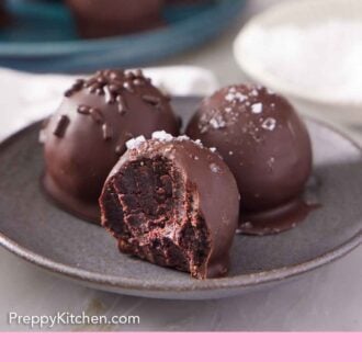 Pinterest graphic of a plate of brownie truffles with the one in front with a bite taken out.