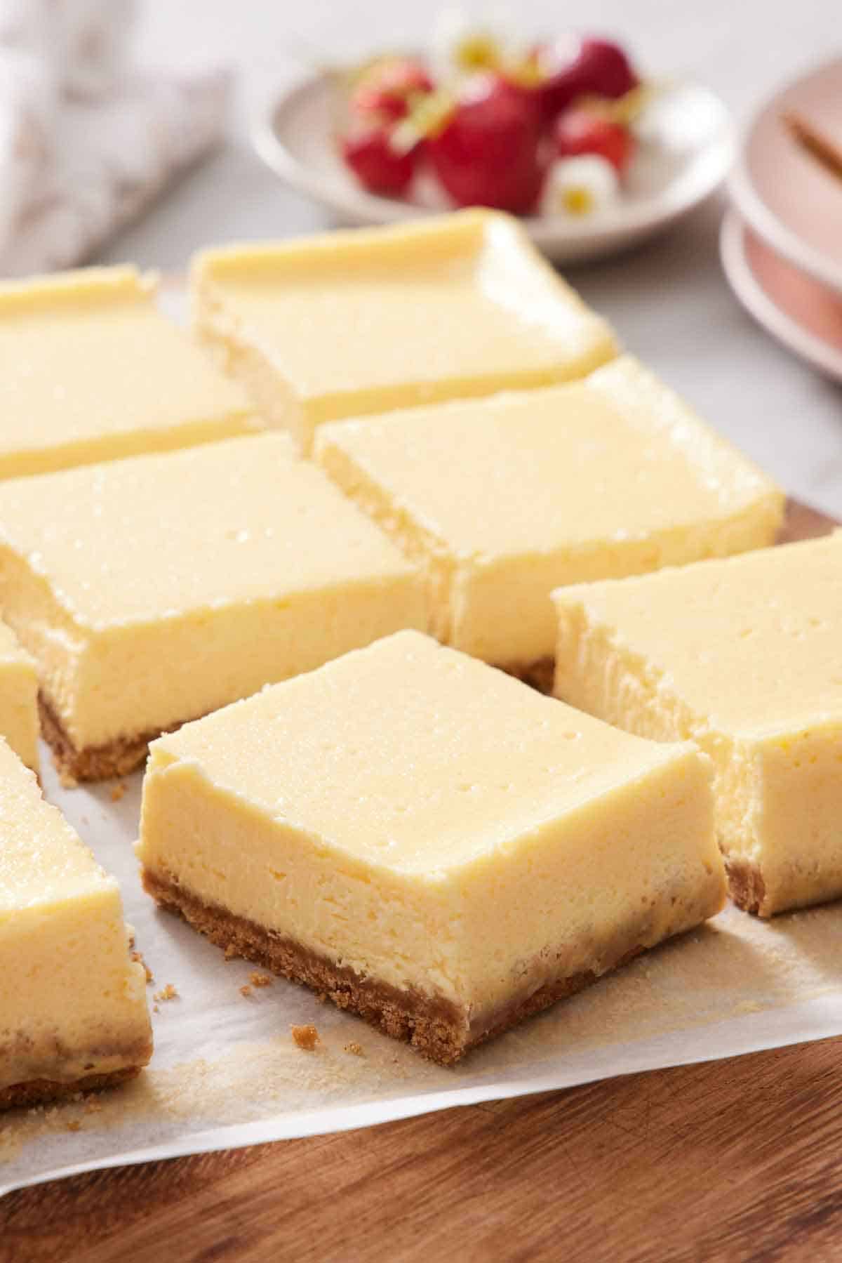 Cheesecake bars freshly sliced on a parchment-lined serving board.