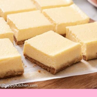 Pinterest graphic of cheesecake bars on a parchment-lined serving board.