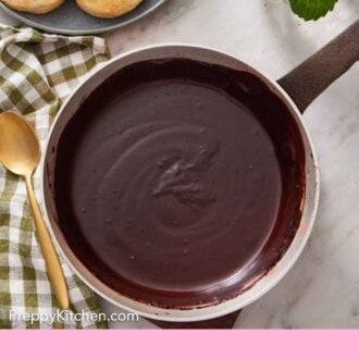 Pinterest graphic of an overhead view of a pot of chocolate gravy. A plate of biscuits off to the side.