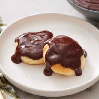 A plate of two biscuits with chocolate gravy on top. A fork and a napkin beside it.