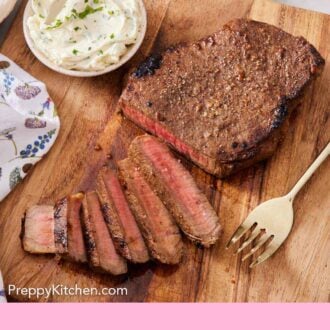 Pinterest graphic of a wooden cutting board with a London broil, half sliced. A fork and a bowl of herb compound butter beside the steak.