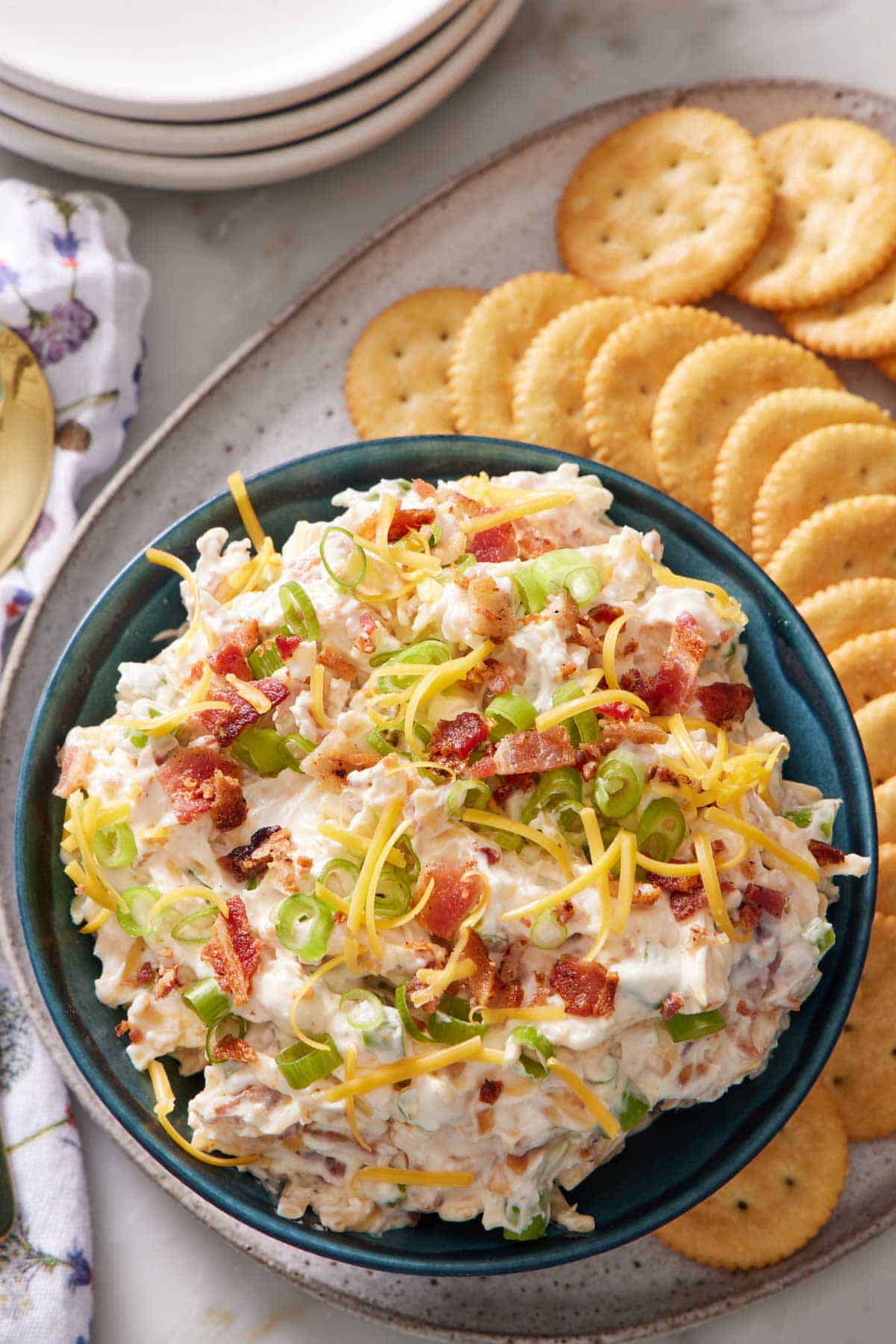 Overhead view of a bowl of million dollar dip on a platter with round crackers.