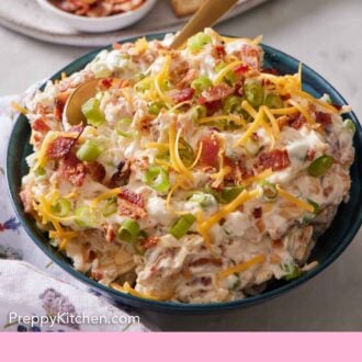 Pinterest graphic of a bowl of million dollar dip with a spoon inside. More toppings and crackers in the background.