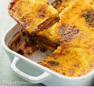 Pinterest graphic of a serving of moussaka lifting from the baking dish.