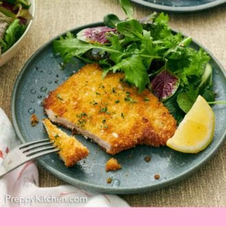 Pinterest graphic of a plate with a schnitzel cut with a bite on a fork along with some mixed greens and lemon wedges.