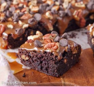 Pinterest graphic of a serving board with turtle brownies with one piece cut out.