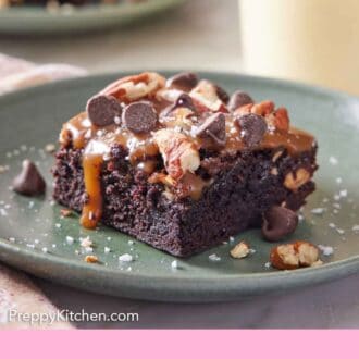 Pinterest graphic of a plate with a piece of turtle brownies with flaky salt sprinkled on top.