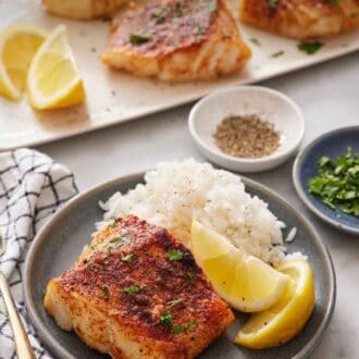 Pinterest graphic of a plate with rice, lemon wedges, and an air fryer cod. A platter with more air fryer cod in the background.