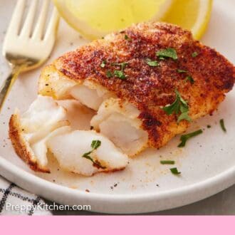 Pinterest graphic of a plate with an air fryer cod with a portion flaked off with two lemon wedges in the background.