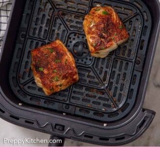 Pinterest graphic of an overhead view of two air fryer cod fillets in an air fryer basket.