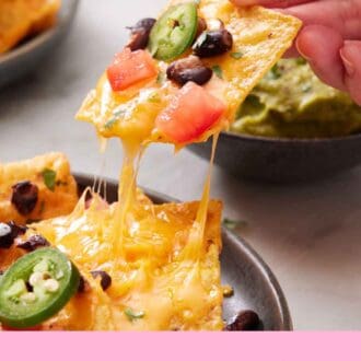 Pinterest graphic of a tortilla chip with cheese, tomatoes, black beans, and jalapeno lifted from a plate of air fryer nachos.