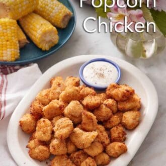 Pinterest graphic of a platter of air fryer popcorn chicken with a bowl of sauce. Corn on the cob in the background along with flowers.