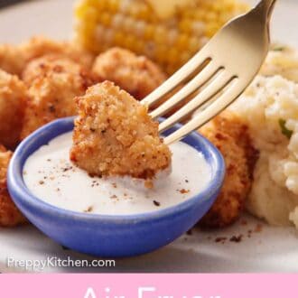 Pinterest graphic of a fork dipping an air fryer popcorn chicken into a small bowl of sauce.