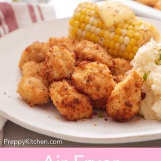 Pinterest graphic of a close up view of air fryer popcorn chicken on a plate with mashed potatoes and a corn on the cob with butter.