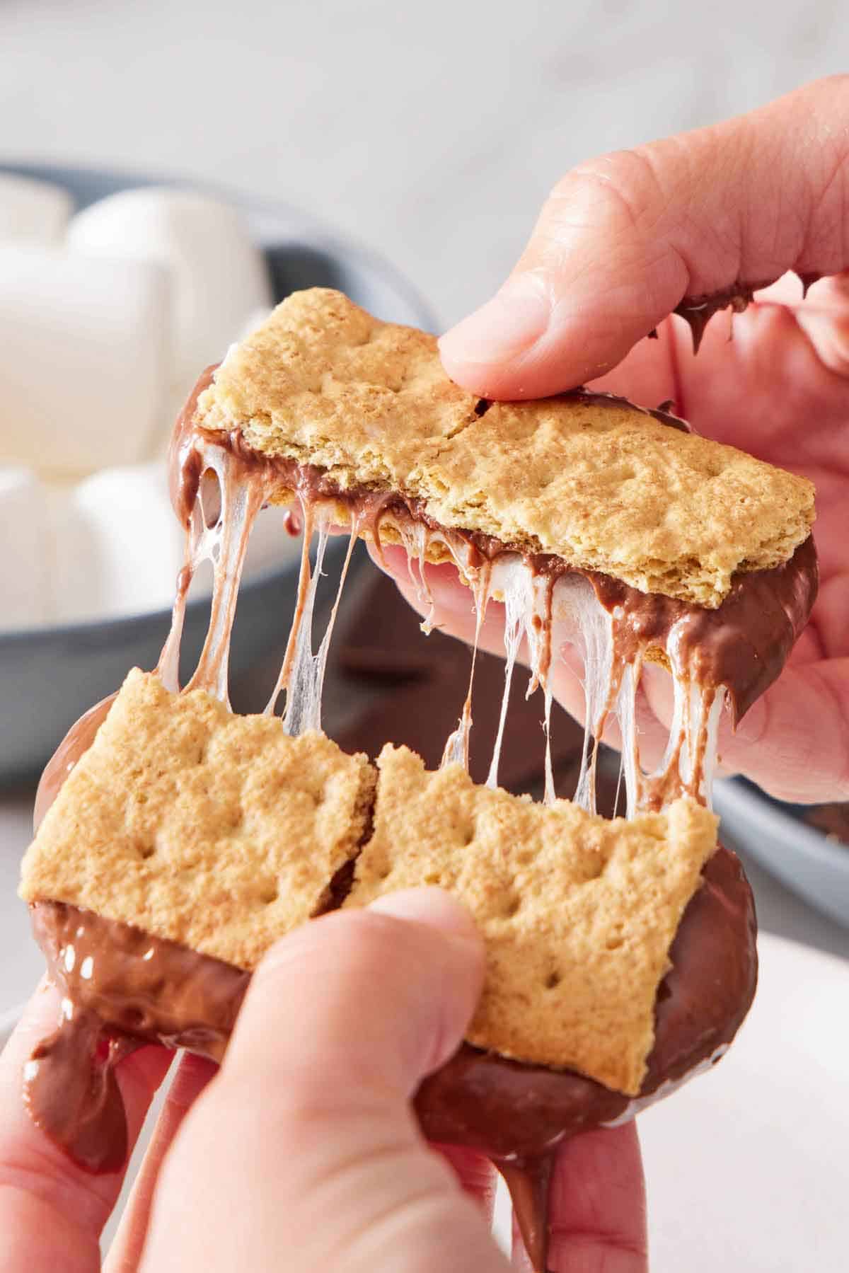 An air fryer s'mores broken in half and showing the melty interior stretched.