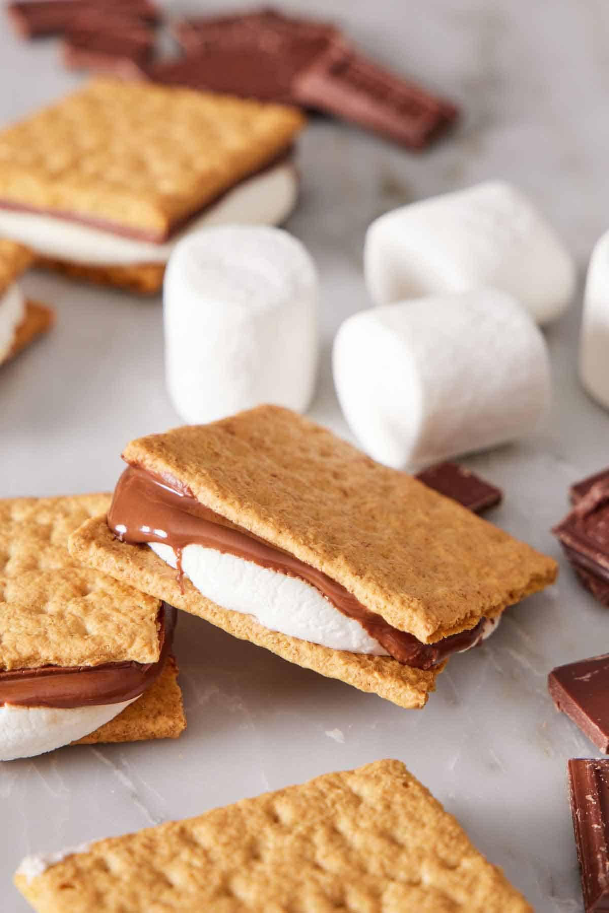 Air fryer s'mores scattered around with marshmallows and chocolate pieces.