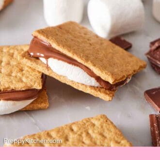 Pinterest graphic of air fryer s'mores scattered around with marshmallows and chocolate pieces.