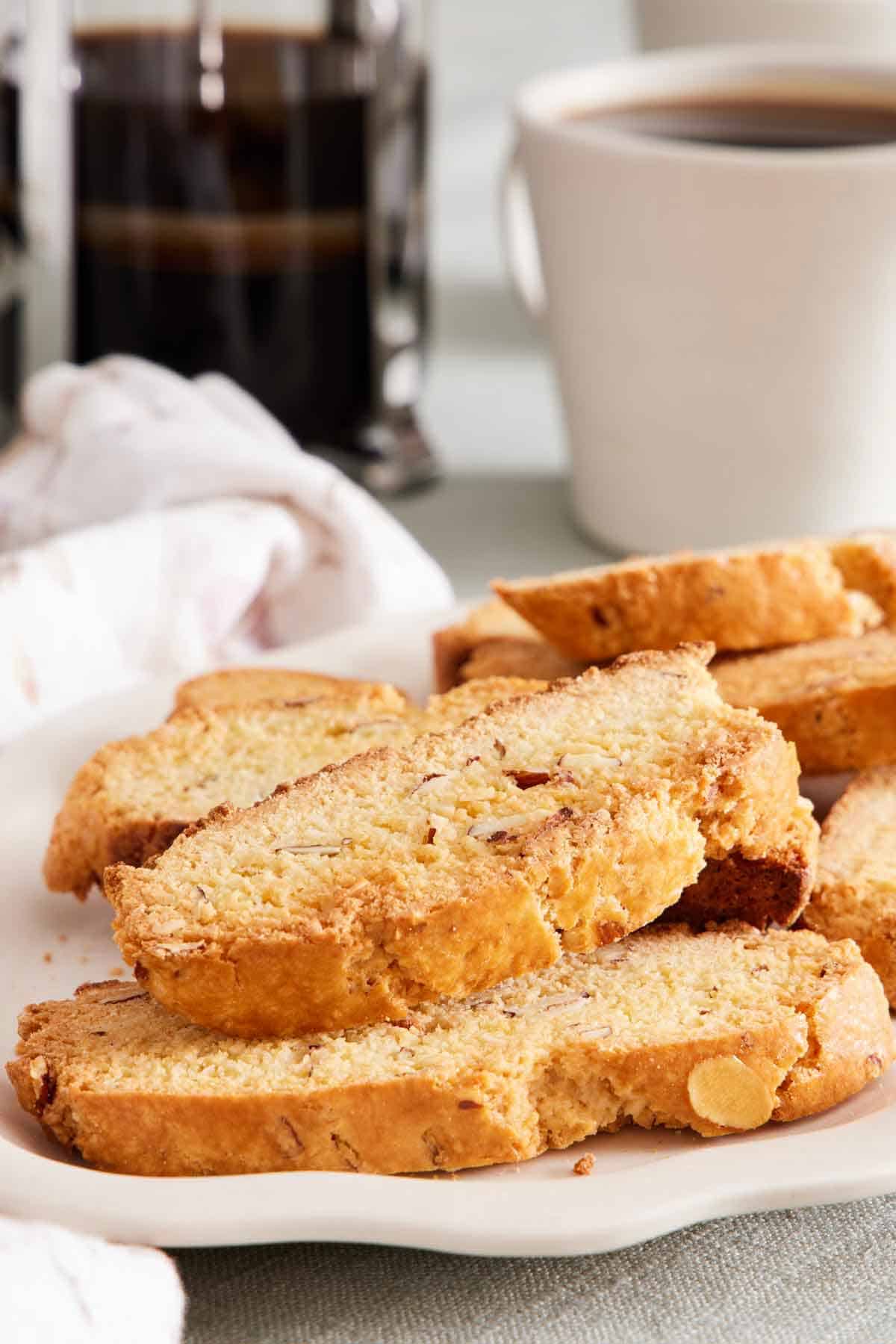 A platter of biscotti with a mug of coffee and a French press in the background.