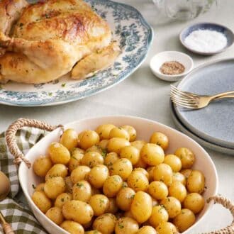 Pinterest graphic of a large bowl of boiled potatoes. A roast chicken in the background along with plates, forks, salt and pepper, flowers, and some mixed greens in a bowl.