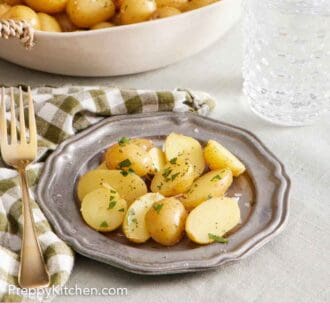 Pinterest graphic of a plate with cut boiled potatoes. A drink in the background along with a large bowl of boiled potatoes.