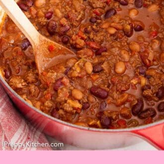 Pinterest graphic of a dutch oven of chili with a wooden spoon inside.