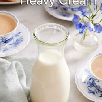 Pinterest graphic of a jar of homemade heavy cream. Three cups of tea with heavy cream in the background along with biscuits and flowers.